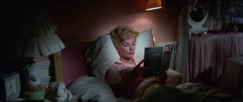 Movie still from “It Happened at the World's Fair” (1963), directed by Norman Taurog – A woman reading a book in a bed; Medium shot, High angle
