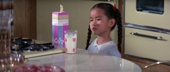 Movie still from “It Happened at the World's Fair” (1963), directed by Norman Taurog – A little girl sitting at a table with a glass of milk in front of her; Close Up shot, High angle