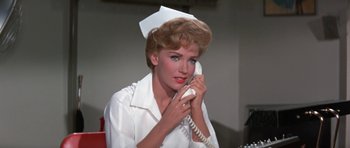 Movie still from “It Happened at the World's Fair” (1963), directed by Norman Taurog – A woman talking on a phone while wearing a nurse's outfit; Close Up shot, Low angle
