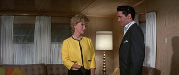 Movie still from “It Happened at the World's Fair” (1963), directed by Norman Taurog – A man and a woman standing next to each other in a room; Medium shot, Over the shoulder angle