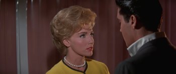 Movie still from “It Happened at the World's Fair” (1963), directed by Norman Taurog – A woman wearing a yellow shirt and a pearl necklace; Close Up shot, Over the shoulder angle