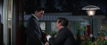 Movie still from “It Happened at the World's Fair” (1963), directed by Norman Taurog – A man in a suit and a man in a tie; Medium shot, Over the shoulder angle