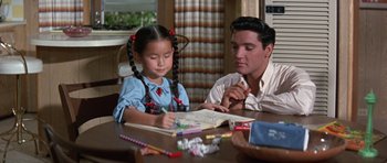 Movie still from “It Happened at the World's Fair” (1963), directed by Norman Taurog – A man and a little girl sitting at a wooden table; Medium shot, Over the shoulder angle