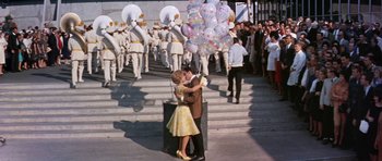 Movie still from “It Happened at the World's Fair” (1963), directed by Norman Taurog – A man and a woman kissing in front of a group of people; Wide shot, High angle