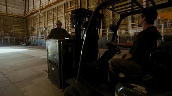 Movie still from “It Might Get Loud” (2008), directed by Davis Guggenheim – A man driving a forklift in a large warehouse; Wide shot, Low angle
