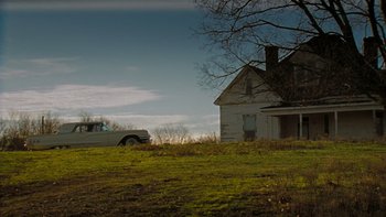 Movie still from “It Might Get Loud” (2008), directed by Davis Guggenheim – An old car parked in front of an abandoned house; Extreme Wide shot, Low angle