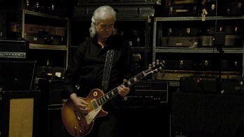 Movie still from “It Might Get Loud” (2008), directed by Davis Guggenheim – A man in a black shirt is playing an electric guitar; Medium shot, Low angle