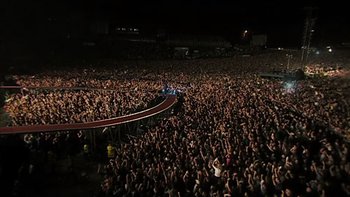 Movie still from “It Might Get Loud” (2008), directed by Davis Guggenheim – A large crowd of people at an event at night; Extreme Wide shot, High angle