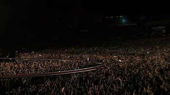 Movie still from “It Might Get Loud” (2008), directed by Davis Guggenheim – A crowd of people in a stadium at night; Extreme Wide shot, High angle