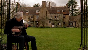 Movie still from “It Might Get Loud” (2008), directed by Davis Guggenheim – An older man playing an instrument in front of an old house; Wide shot, Low angle