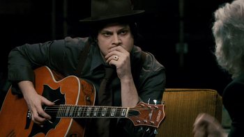 Movie still from “It Might Get Loud” (2008), directed by Davis Guggenheim – A man in a hat and a tie holding a guitar; Close Up shot, High angle
