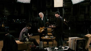 Movie still from “It Might Get Loud” (2008), directed by Davis Guggenheim – A group of people that are sitting around a room together; Wide shot, High angle