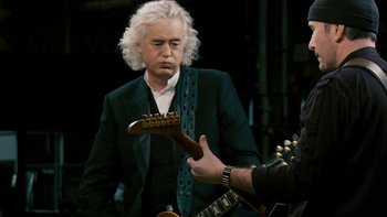 Movie still from “It Might Get Loud” (2008), directed by Davis Guggenheim – A man in a black suit is holding a guitar; Close Up shot, Over the shoulder angle