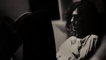 Movie still from “It Might Get Loud” (2008), directed by Davis Guggenheim – A black and white photo of a man with curly hair; Medium shot, Low angle