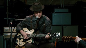 Movie still from “It Might Get Loud” (2008), directed by Davis Guggenheim – A man in a hat playing an electric guitar; Medium shot, High angle