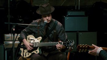 Movie still from “It Might Get Loud” (2008), directed by Davis Guggenheim – A man in a hat playing an electric guitar; Medium shot, High angle