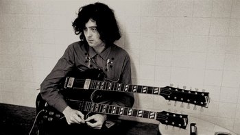 Movie still from “It Might Get Loud” (2008), directed by Davis Guggenheim – A man holding a guitar in front of a wall; Medium shot, High angle