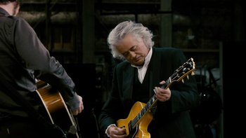 Movie still from “It Might Get Loud” (2008), directed by Davis Guggenheim – An older man is playing an electric guitar; Medium shot, Over the shoulder angle