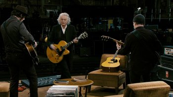 Movie still from “It Might Get Loud” (2008), directed by Davis Guggenheim – A group of people playing guitars in a room; Wide shot, High angle