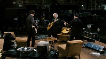 Movie still from “It Might Get Loud” (2008), directed by Davis Guggenheim – A group of men playing guitars in a living room; Wide shot, High angle