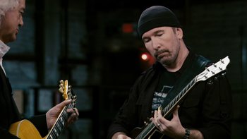 Movie still from “It Might Get Loud” (2008), directed by Davis Guggenheim – A man holding a guitar while another man holds another guitar; Close Up shot, Low angle