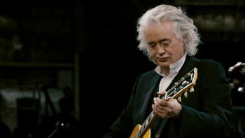 Movie still from “It Might Get Loud” (2008), directed by Davis Guggenheim – An older man holding a guitar while wearing a suit; Close Up shot, Low angle