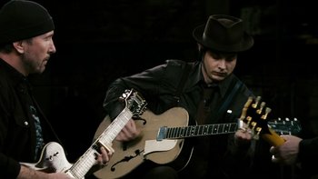 Movie still from “It Might Get Loud” (2008), directed by Davis Guggenheim – A man in a hat playing an instrument; Medium shot, High angle
