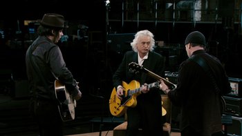 Movie still from “It Might Get Loud” (2008), directed by Davis Guggenheim – A group of people that are standing up with guitars; Medium shot, High angle