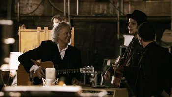 Movie still from “It Might Get Loud” (2008), directed by Davis Guggenheim – A man playing a guitar while another man plays a guitar; Medium shot, Over the shoulder angle