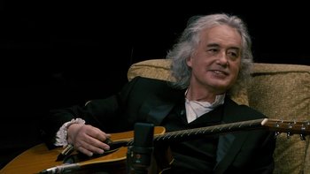 Movie still from “It Might Get Loud” (2008), directed by Davis Guggenheim – A man sitting in a chair holding a guitar; Close Up shot, High angle