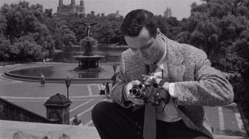Movie still from “It Should Happen to You” (1954), directed by George Cukor – A black and white photo of a man taking a picture; Medium shot, Low angle