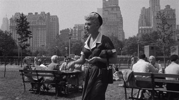 Movie still from “It Should Happen to You” (1954), directed by George Cukor – An older woman standing in a park holding a plate; Wide shot, Low angle