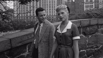 Movie still from “It Should Happen to You” (1954), directed by George Cukor – A man and a woman standing next to each other on a bridge; Medium shot, High angle