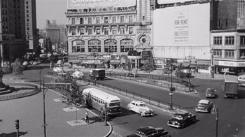 Movie still from “It Should Happen to You” (1954), directed by George Cukor – A black and white photo of a city street with cars and buses; Extreme Wide shot, High angle
