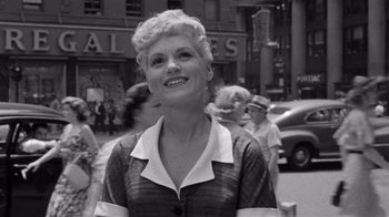 Movie still from “It Should Happen to You” (1954), directed by George Cukor – An old photo of a woman smiling in the street; Medium shot, Over the shoulder angle