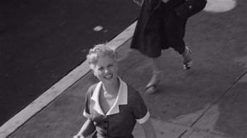 Movie still from “It Should Happen to You” (1954), directed by George Cukor – An old black and white photo of a woman smiling; Extreme Wide shot, High angle