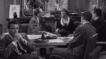 Movie still from “It Should Happen to You” (1954), directed by George Cukor – An older man and woman sitting at a table with other people; Medium shot, High angle