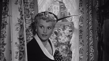Movie still from “It Should Happen to You” (1954), directed by George Cukor – An old photo of a woman wearing a hat with a feather in her hair; Close Up shot, Low angle