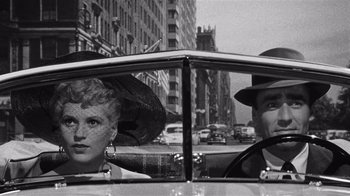 Movie still from “It Should Happen to You” (1954), directed by George Cukor – A man and a woman in a car on a street; Close Up shot, Low angle