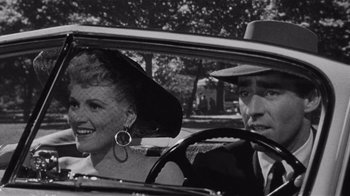 Movie still from “It Should Happen to You” (1954), directed by George Cukor – An old photo of a man and a woman in a car; Close Up shot, High angle