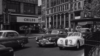 Movie still from “It Should Happen to You” (1954), directed by George Cukor – A black and white photo of cars on a city street; Extreme Wide shot, High angle