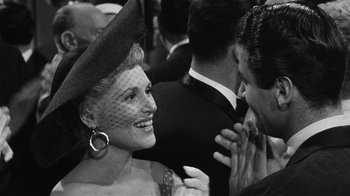 Movie still from “It Should Happen to You” (1954), directed by George Cukor – A woman wearing a hat is talking to a man in a suit; Close Up shot, Over the shoulder angle