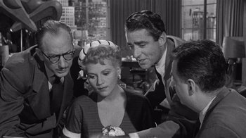 Movie still from “It Should Happen to You” (1954), directed by George Cukor – A black and white photo of a group of people gathered together; Medium shot, High angle