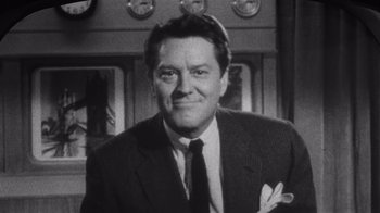 Movie still from “It Should Happen to You” (1954), directed by George Cukor – Black and white photograph of a man wearing a suit and tie; Close Up shot, Low angle
