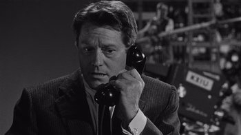 Movie still from “It Should Happen to You” (1954), directed by George Cukor – A black and white photo of a man holding a phone to his ear; Close Up shot, High angle