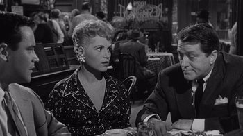 Movie still from “It Should Happen to You” (1954), directed by George Cukor – A woman sitting next to a man at a table; Medium shot, Over the shoulder angle