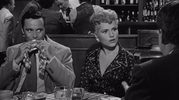 Movie still from “It Should Happen to You” (1954), directed by George Cukor – An older woman sitting at a table in front of two men; Medium shot, Over the shoulder angle