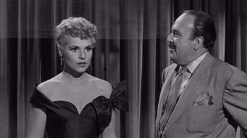 Movie still from “It Should Happen to You” (1954), directed by George Cukor – An old black and white photo of a man and a woman; Medium shot, Over the shoulder angle