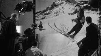 Movie still from “It Should Happen to You” (1954), directed by George Cukor – An old photo of a man on skis in the snow; Wide shot, Low angle