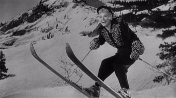 Movie still from “It Should Happen to You” (1954), directed by George Cukor – An old photo of a woman on skis in the snow; Medium shot, Low angle